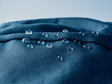 Water Drops On Waterproof Membrane Fabric. Detail View Of Texture Of Blue Waterproof Cloth.