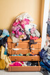 open chest drawers with drop-down clothes and piles of clothes around in a mess