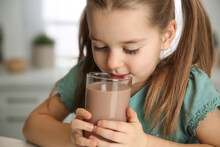 Cute Little Child Drinking Tasty Chocolate Milk In Kitchen, Closeup
