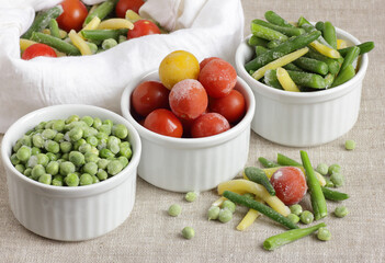 Frozen vegetables assorted in bowls isolated on white background, closeup, saving leftovers, food storage concept and eating meals at home concept