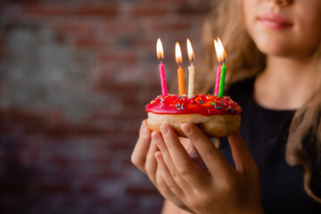 Happy little girl makes a wish and blows out candles on a cake on her birthday