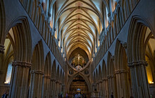Straight On View Through The Nave Showing The Ribbed, Arched Ceiling With The Inverted Arch, The Crucifix And The Side Columns In A Vertical Format Of The Wells Cathedral In Wells, Somerset, England.
