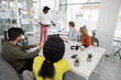 © sofiko14 - Young african man, standing near flipchart, and presenting details of joint project for multiracial team
