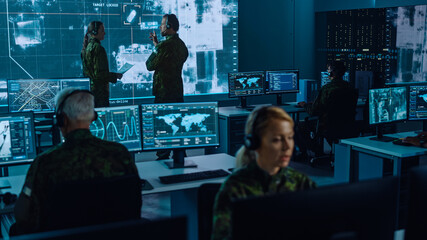 Fototapete - Military Surveillance Team of Officers Locked a Target on a Vehicle from a Satellite and Monitor it on a Big Display in Office for Cyber Operations for Managing Security and Army Communications. 