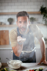 Wall Mural - Young man preparing bread at home. Happy man having fun while baking a fresh pasta..