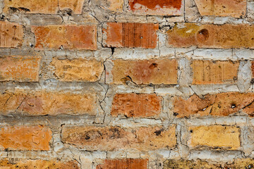 Symmetrical brick wall background. Red and brown colored terracotta bricks from an abandoned house, some clean, some dirty. Cracks in the wall.