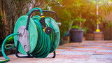The old water hose roll up with nozzle on tile floor in home gardening area