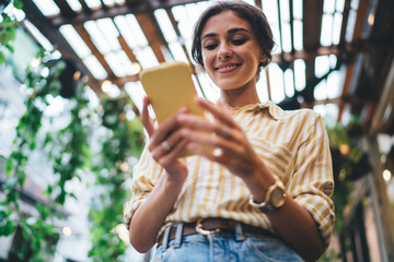 smiling young ethnic lady using smartphone in cafe