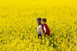 © Belphnaque - Pretty teenager girl with his little brother together enjoy the sunshine in the middle of a yellow flower field.