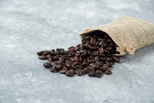 Roasted Coffee Beans Out Of Burlap Sack On Marble Background