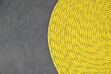 Yellow paracord with gray veins, coiled in a tight spiral on the right side of the image.