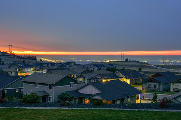 Sunset view from a hilltop in Liberty Lake overlooking the cities of Spokane and Spokane Valley with Sprague Avenue illuminated at night.