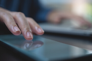 Close up of woman finger touching on mobile smartphone screen during working on laptop computer