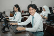 © Odua Images - Indonesian high school students smile looking at the camera while using a computer PC with their friends