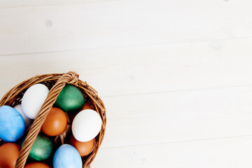 painted Easter eggs in a basket on a light background top view