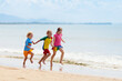 © famveldman - Kids playing on beach. Children play at sea.