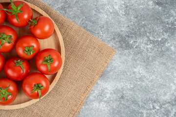 Wooden plate of fresh organic tomatoes on marble background