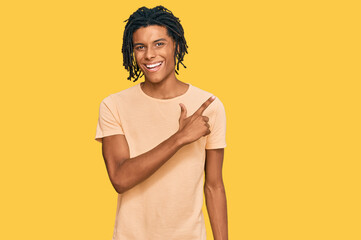 Wall Mural - Young african american man wearing casual clothes cheerful with a smile of face pointing with hand and finger up to the side with happy and natural expression on face