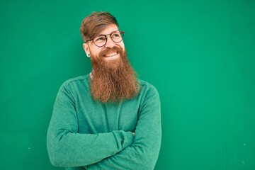 Sticker - Young irish man with arms crossed and smiling happy leaning on the wall at the city.