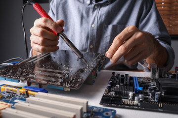 Wall Mural - Technician repairing electronic circuit board with soldering iron at table, closeup