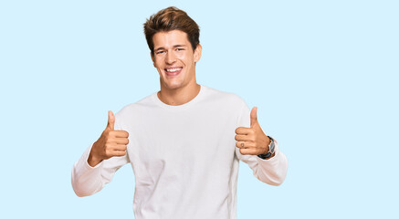 Handsome caucasian man wearing casual white sweater success sign doing positive gesture with hand, thumbs up smiling and happy. cheerful expression and winner gesture.