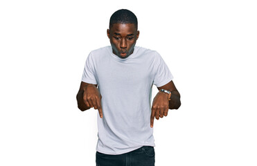 Young african american man wearing casual white t shirt pointing down with fingers showing advertisement, surprised face and open mouth