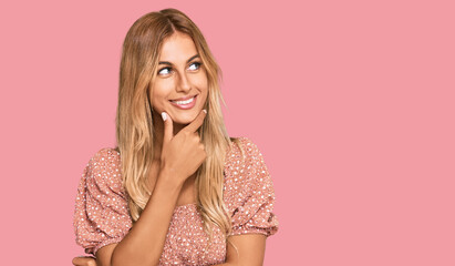 Wall Mural - Beautiful blonde young woman wearing summer top with hand on chin thinking about question, pensive expression. smiling with thoughtful face. doubt concept.