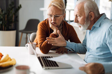 Wall Mural -  Frustrated senior couple sitting at home and checking their home finance