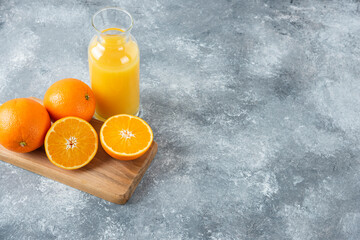 Wall Mural - Glass pitcher of juice with sliced orange fruit on a wooden board