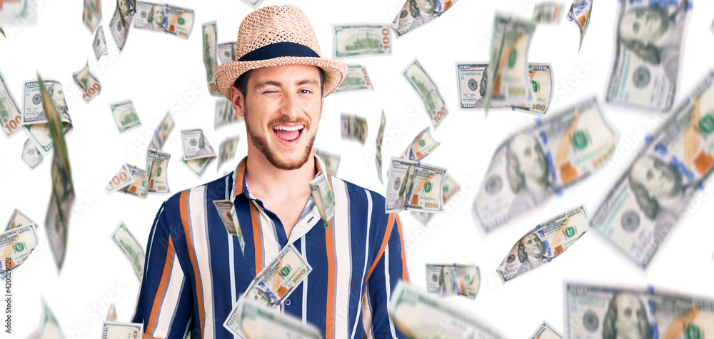 Young handsome caucasian man wearing summer hat winking looking at the camera with sexy expression, cheerful and happy face.