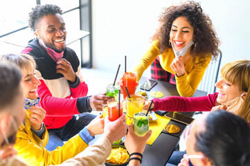 Canvas Print - Multicultural  young friends toast and drinking cocktail with open face mask - New normal lifestyle concept with millennials having fun together talking at cocktail bar