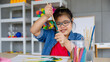 © Bangkok Click Studio - Young Asian down syndrome little girl sitting at desk with colors and painting with concentrated and calm. painting. Concept for education for disabled kid