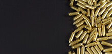 Many Brass Gun Bullets On Black Table Closeup View From Above, Space For Text Left Side