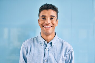 Young latin man smiling happy walking at the city.