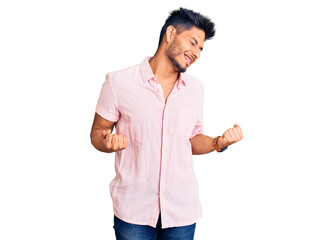 Handsome latin american young man wearing casual summer shirt very happy and excited doing winner gesture with arms raised, smiling and screaming for success. celebration concept.