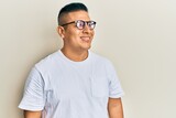 Fototapeta Do przedpokoju - Young latin man wearing casual clothes and glasses looking to side, relax profile pose with natural face and confident smile.