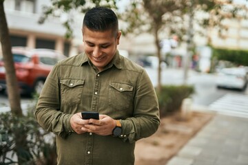 Canvas Print - Young latin man smiling happy using smartphone at the city.