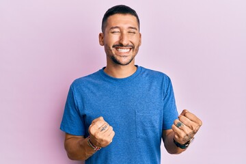 Sticker - Handsome man with tattoos wearing blue tshirt clothes celebrating surprised and amazed for success with arms raised and eyes closed