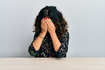 Canvas Print - Beautiful middle age woman wearing casual clothes sitting on the table with sad expression covering face with hands while crying. depression concept.