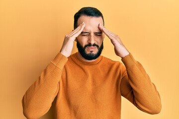 Young man with beard wearing casual winter sweater with hand on head for pain in head because stress. suffering migraine.