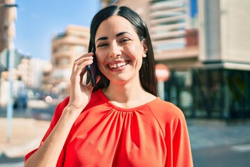 Wall Mural - Young latin girl smiling happy talking on the smartphone at the city.