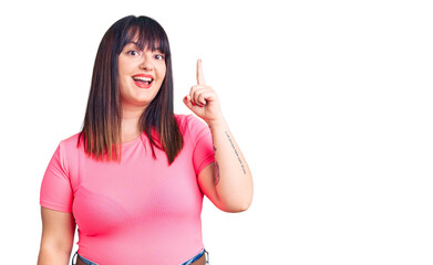 Young plus size woman wearing casual clothes pointing finger up with successful idea. exited and happy. number one.