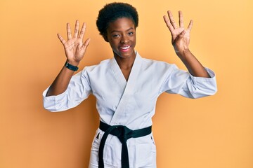 Canvas Print - Young african american girl wearing karate kimono and black belt showing and pointing up with fingers number nine while smiling confident and happy.