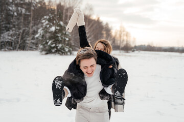 Beautiful young couple hugging in winter park, couple play outside at winter time