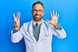© Krakenimages.com - Handsome middle age man wearing doctor uniform and stethoscope showing and pointing up with fingers number eight while smiling confident and happy.