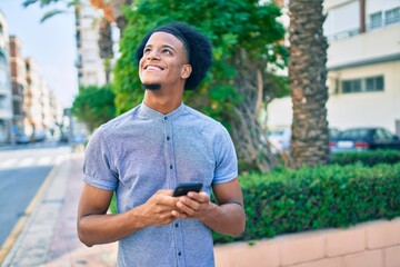 Young african american man smiling happy using smartphone at the city.