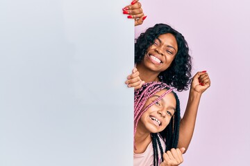 Poster - Beautiful african american mother and daughter holding blank empty banner screaming proud, celebrating victory and success very excited with raised arm