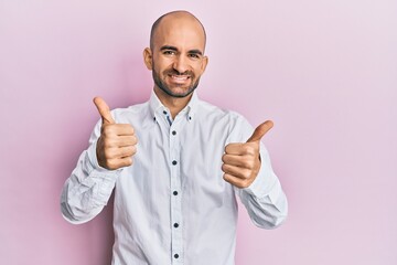 Young hispanic man wearing casual clothes approving doing positive gesture with hand, thumbs up smiling and happy for success. winner gesture.