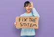 © Krakenimages.com - Young hispanic woman holding fix the system banner cardboard smiling happy doing ok sign with hand on eye looking through fingers