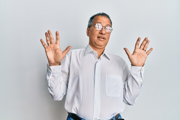 Canvas Print - Middle age indian man wearing casual clothes and glasses afraid and terrified with fear expression stop gesture with hands, shouting in shock. panic concept.